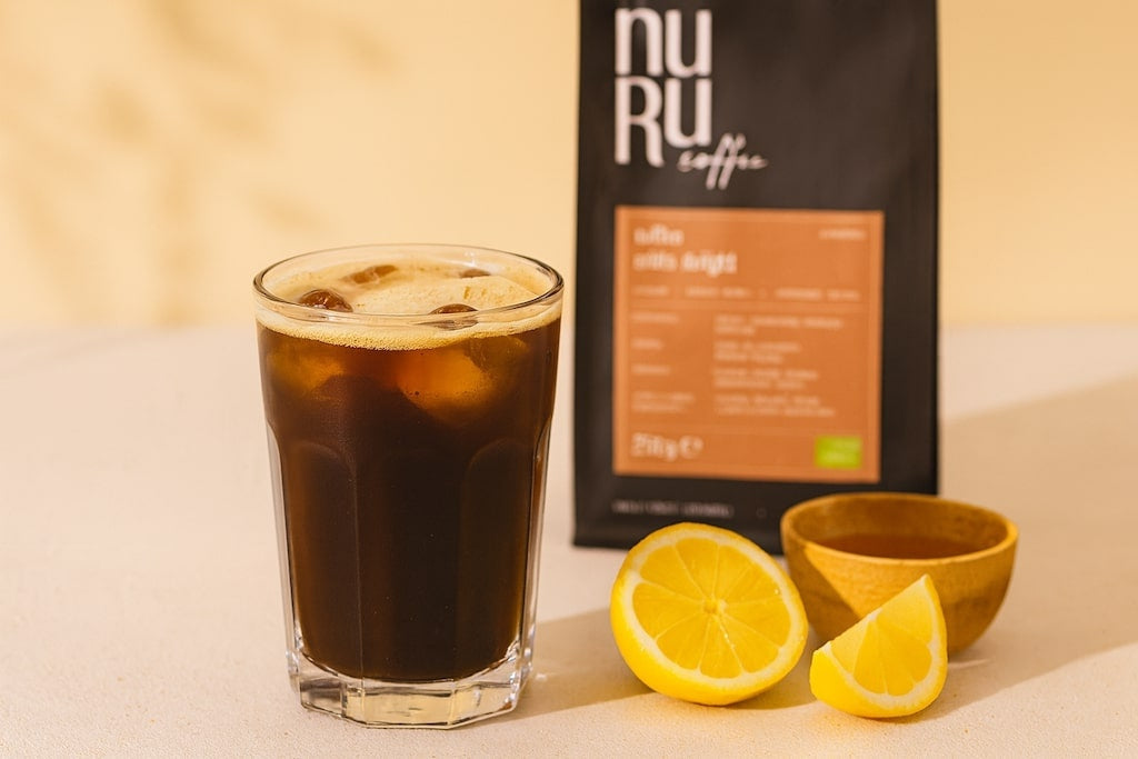 Cold Brew mit Zitronenscheiben und Honig, nuruCoffee Verpackung verschwommen im Hintergrund