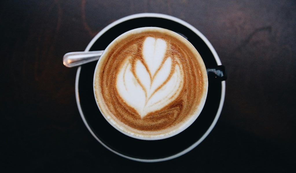 Schwarze Tasse mit entkoffeiniertem Kaffee und Latte Art auf dunklem Hintergrund