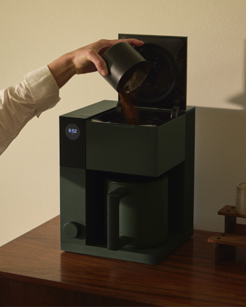 Person füllt gemahlenen Kaffee in grüne Fellow Aiden Preciscion Kaffeemaschine - nuruCoffee