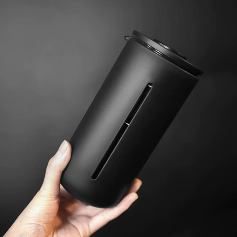 Hand hält Timemore French Press vor dunklem Hintergrund - nuruCoffee