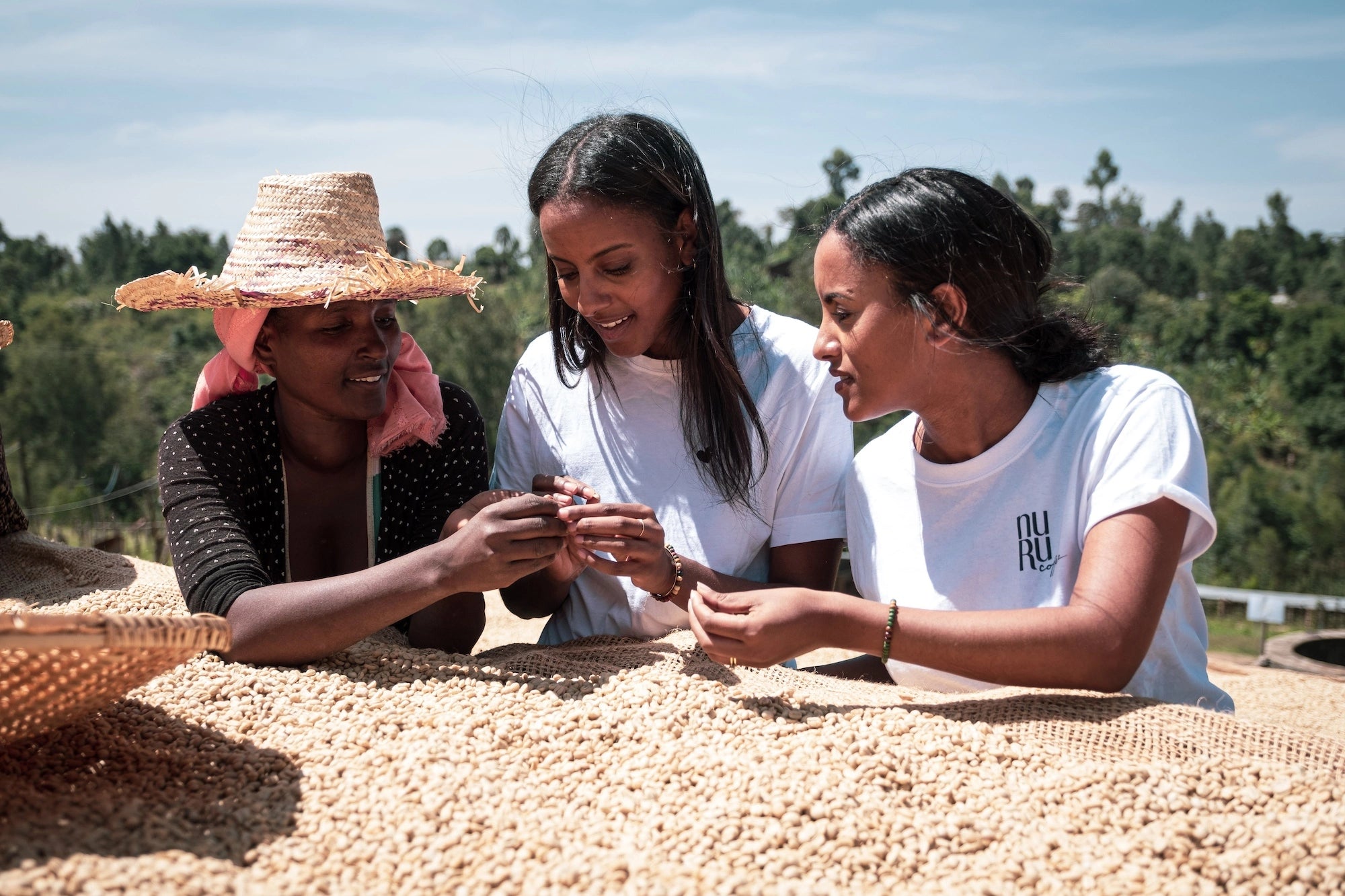 Sali und Sara Nuru mit Kaffeebäuerin und Kaffeebohnen