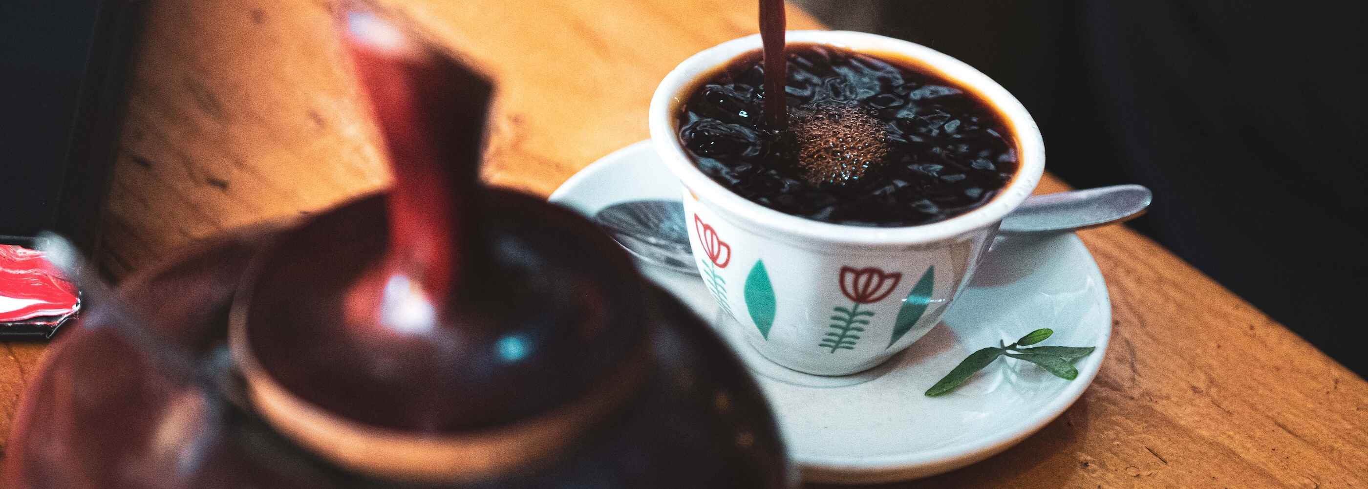 Schwarzer Kaffee wird in bunt bemalte Tasse gegossen