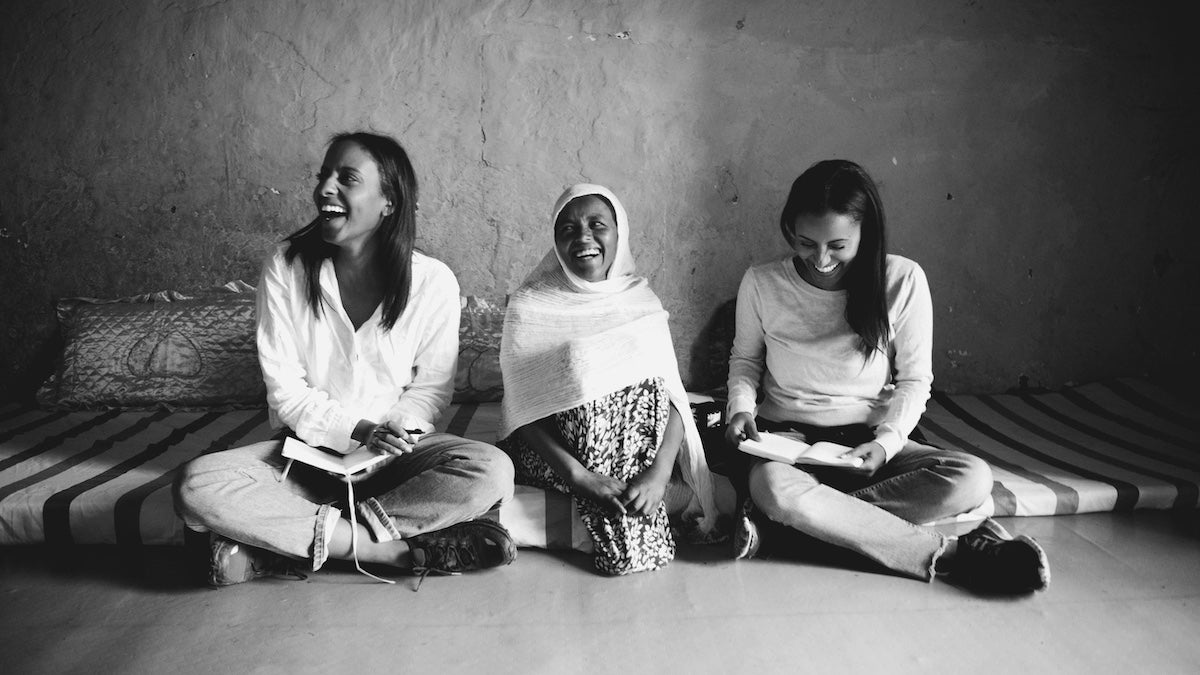 Sali und Sara Nuru sitzen lachend mit Frau in Äthiopien am Boden