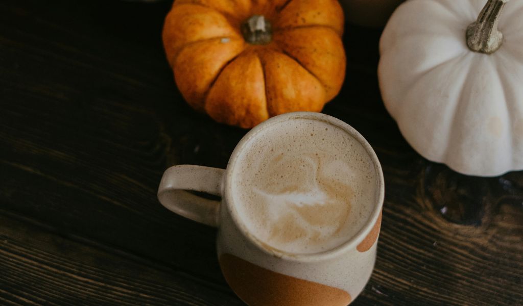 Herbst Kaffee in der Tasse mit Kürbis auf dunklem Holz