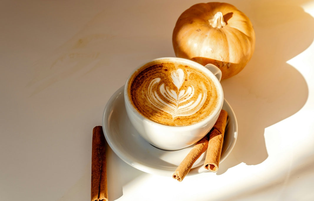 Pumpkin Spice Latte in der Tasse mit Zimtstangen und Kürbis