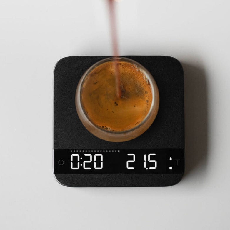 Acaia Lunar Waage in schwarz mit Kaffeetasse in die Kaffee gegossen wird, LED-Anzeige leuchtet - nurucoffee