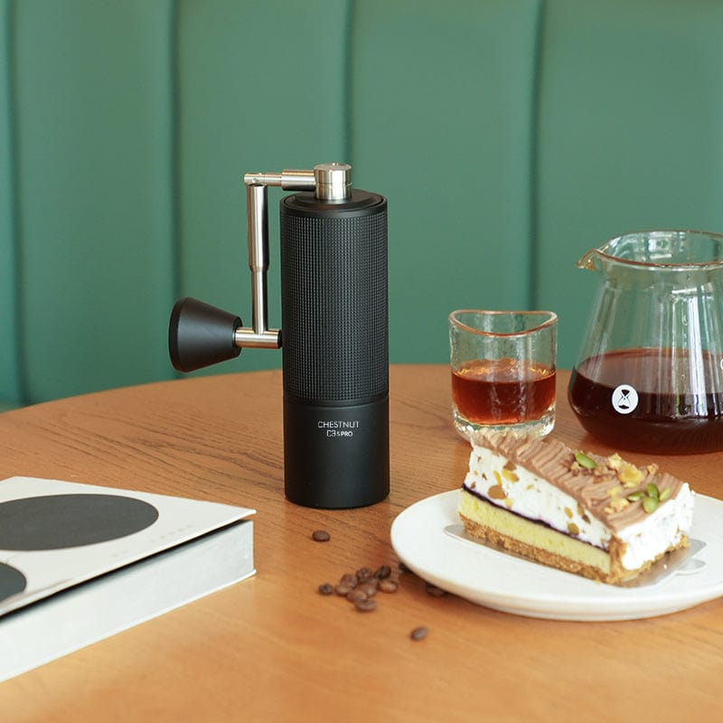 Timemore Chestnut C3S Pro Handmühle auf Tisch mit Kuchen und Kaffee
