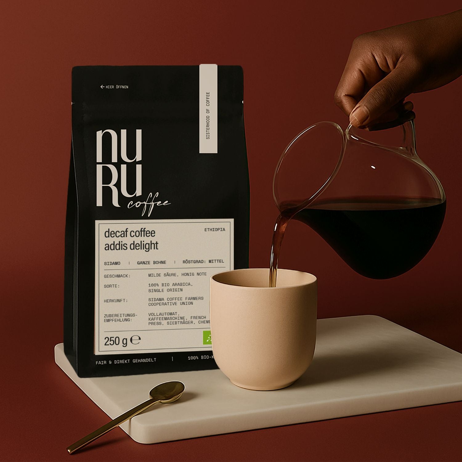 Entkoffeinierter Bio Kaffee Verpackung auf Steinplatte, Hand gießt Kaffee in Becher